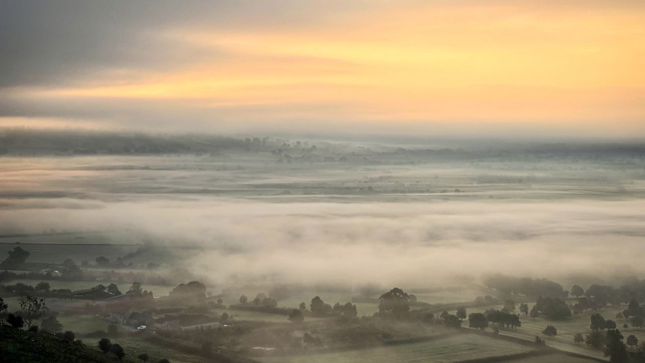The rising sun tries to break through the mist near the town of Glastonbury in southwest England on fall equinox 2021.
