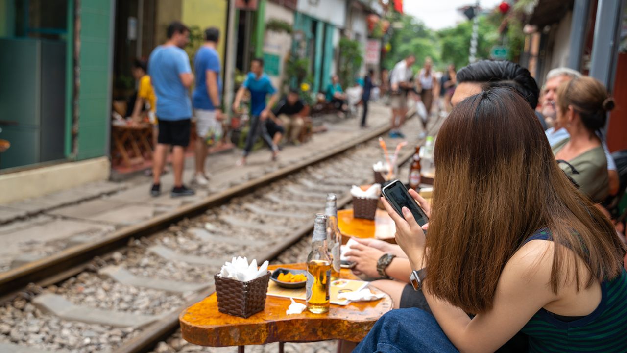 People drink coffee waiting for train to arrive on railway road in Hanoi, Vietnam.