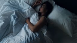 Young beautiful girl or woman sleeping alone in big bed at night, top view.