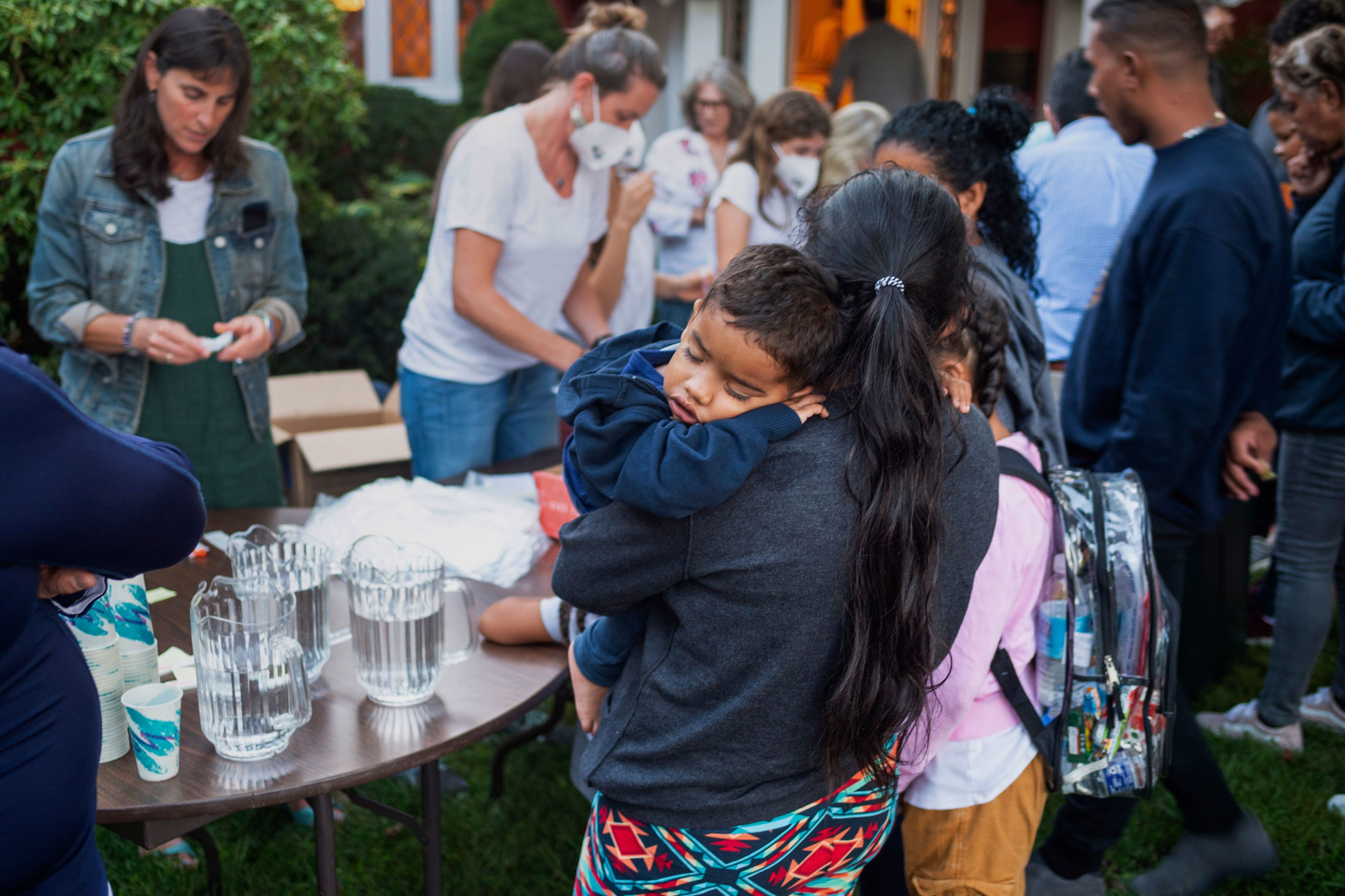 A woman holds a child as a group of migrants is fed outside a church in Edgartown, Massachusetts, on Wednesday, September 14.