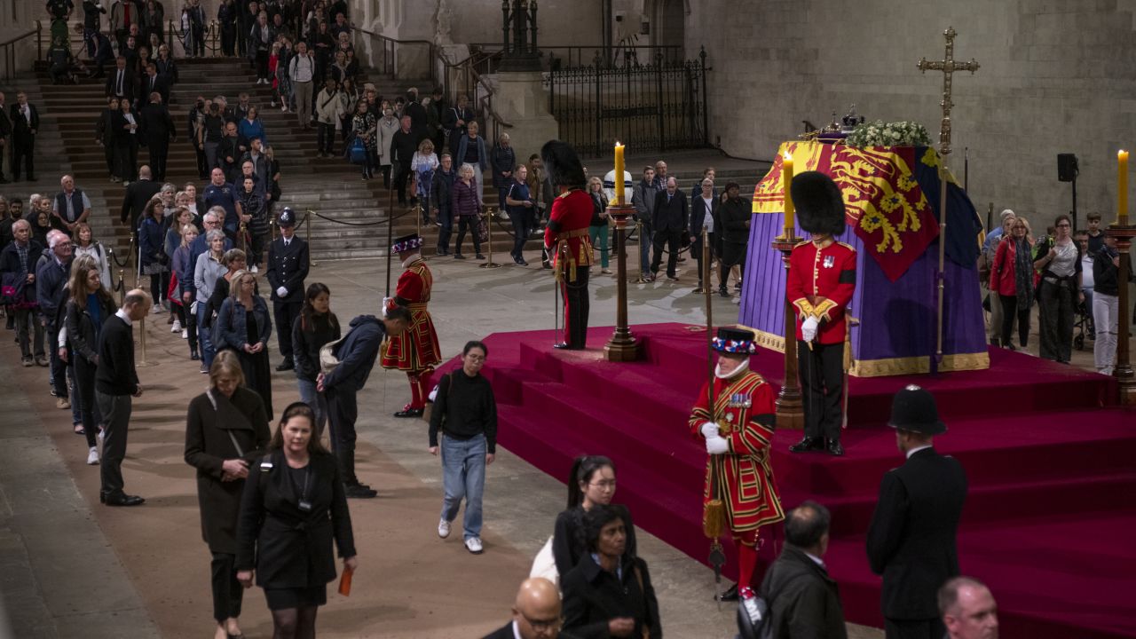 Members of the public view the Queen's coffin, which is draped with the Royal Standard, on which lie the Instruments of State -- the Imperial State Crown and the Orb and Sceptre. 