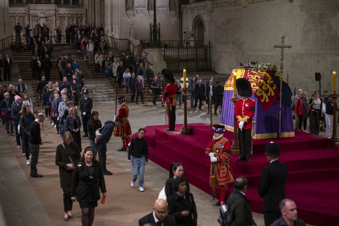 Members of the public view the Queen's coffin, which is draped with the Royal Standard, on which lie the Instruments of State -- the Imperial State Crown and the Orb and Sceptre. 