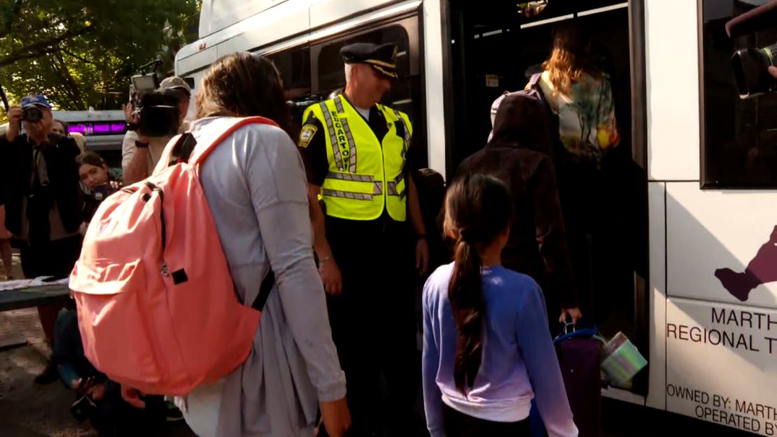 Migrants on Martha's Vineyard board buses Friday that took them to a military base on Cape Cod. 