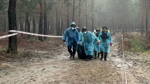 Body bags are taken to refrigerated containers following the exhumation at Izium's mass burial site.