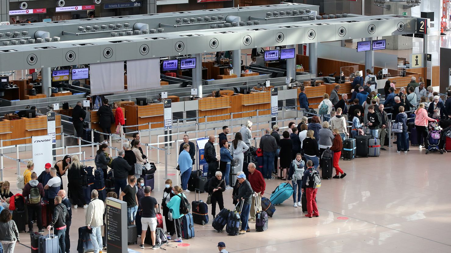 Passengers stand in line as delays and cancellations hit Hamburg Airport.