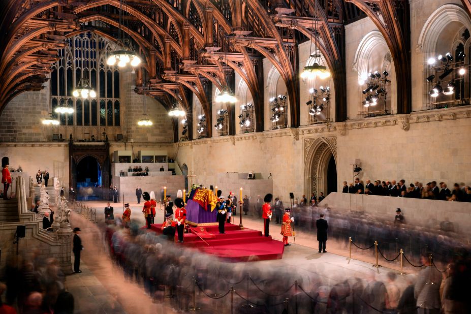 In this photograph taken with a long exposure, the Queen's children stand vigil as members of the public walk around her coffin on Friday.