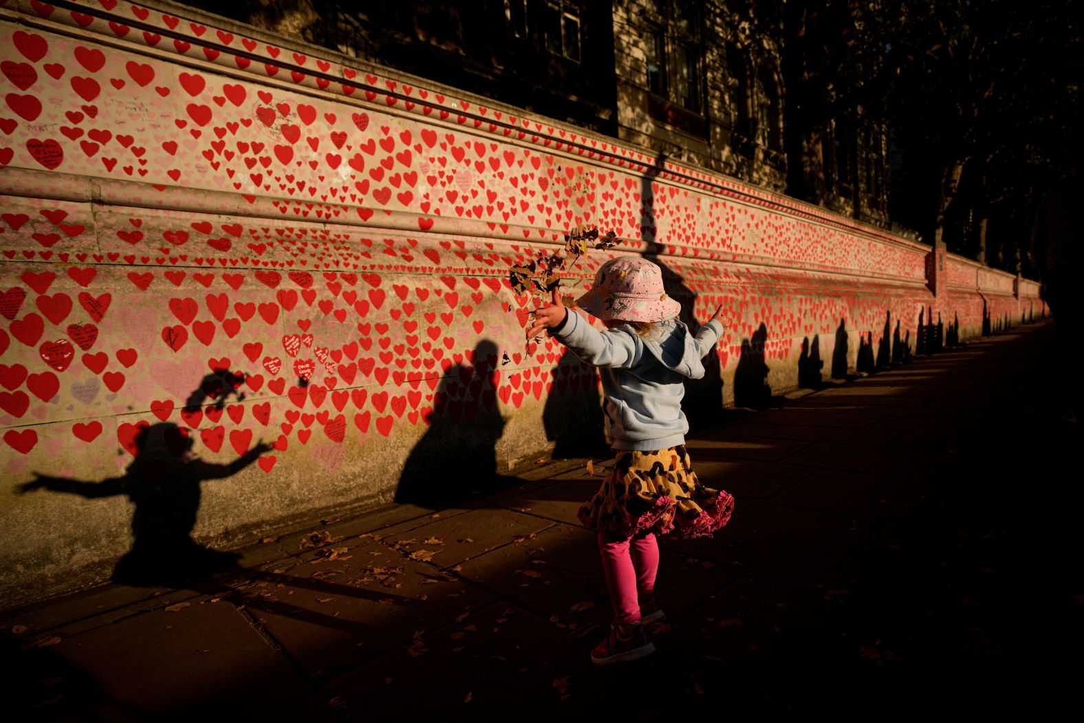 Ellie, 2, throws fallen leaves in the air as people wait in line to pay tribute to the Queen on Friday.