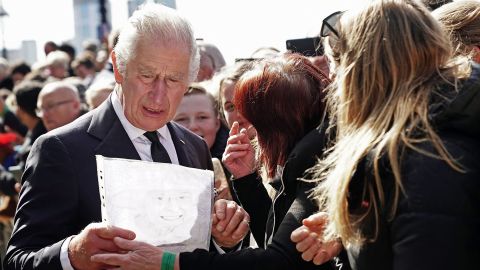 يتفاعل الملك تشارلز عندما يسلمه أحد أفراد الجمهور رسمًا لوالدته الراحلة ، حيث يلتقي بأشخاص ينتظرون في طابور لتقديم الاحترام في استلقاء الملكة في الولاية في 17 سبتمبر 2022.
