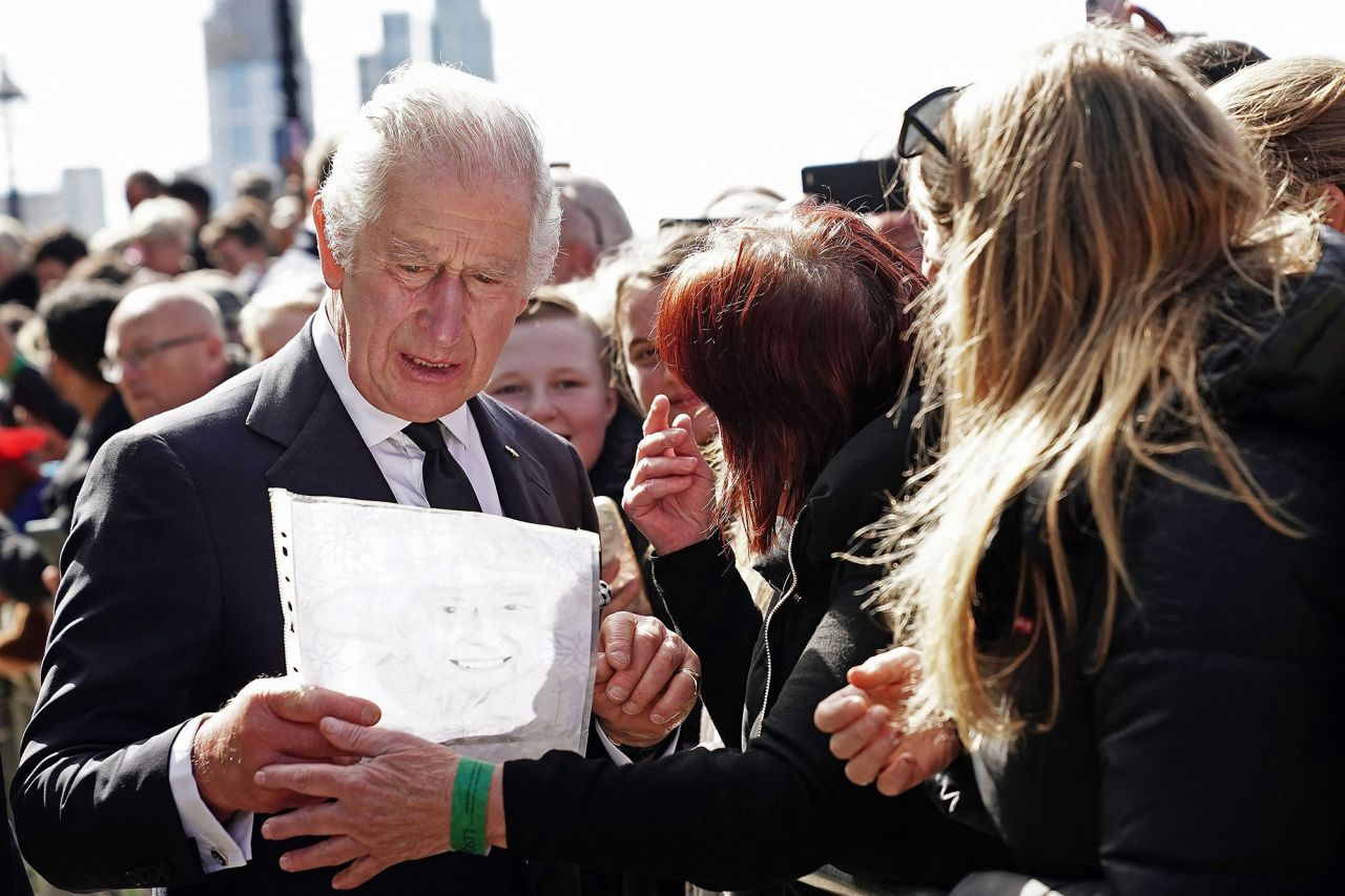 King Charles III reacts as a member of the public hands him a drawing of his mother on Saturday. The King and Prince William were shaking hands with people waiting in line to view the Queen's coffin.