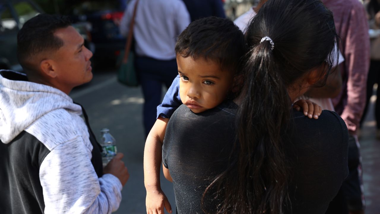 A mother stands outside St. Andrew's church with her child. The migrants were fed lunch with donated food from the community.