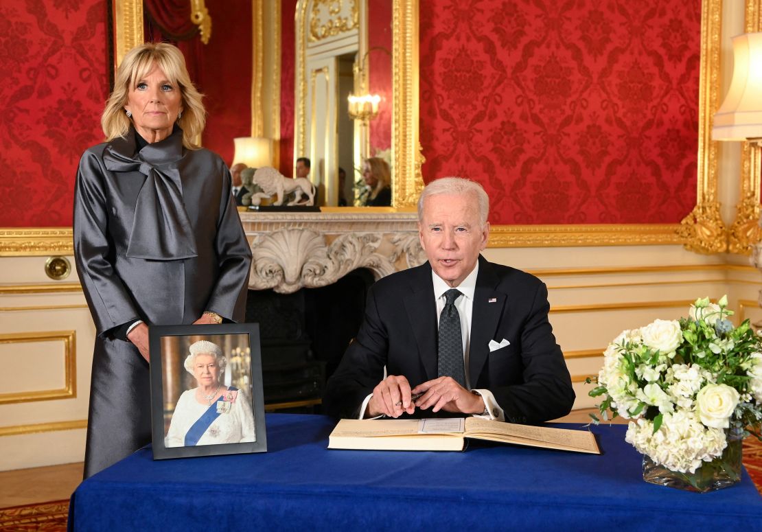 President Joe Biden, accompanied by first lady Jill Biden, signs a condolence book at Lancaster House in London.