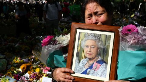 A member of the public holds a portrait of late Queen Elizabeth II as she comes to leave a tribute in Green Park in London on September 18.