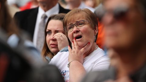 People react while watching coverage of the funeral from outside Windsor Castle.