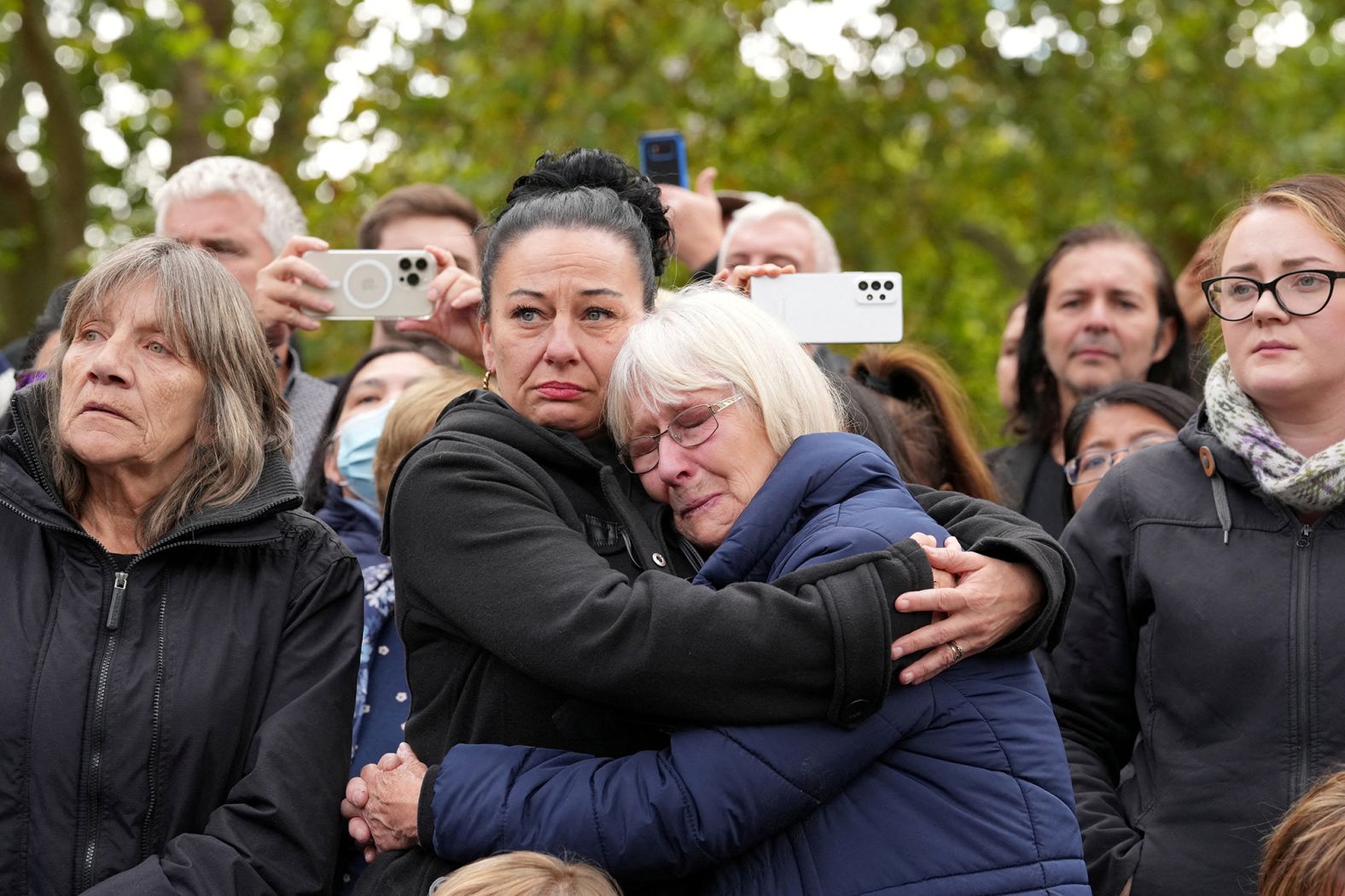 People in London react while watching the funeral procession.