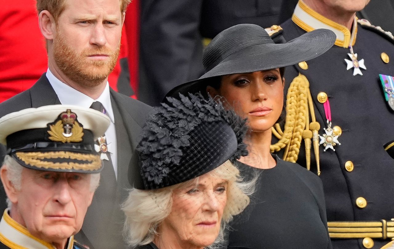 The King and his wife Camilla, the Queen Consort, are seen in front of Prince Harry and his wife Meghan, the Duchess of Sussex, as they watch the Queen's coffin be placed into a hearse following Monday's funeral.