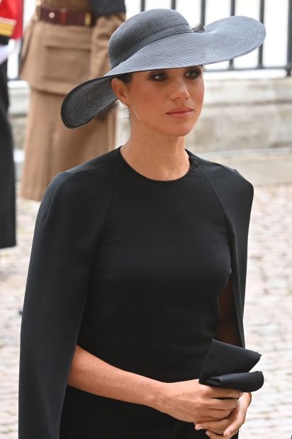 Meghan, Duchess of Sussex arrives at Westminster Abbey in a caped black ensemble.