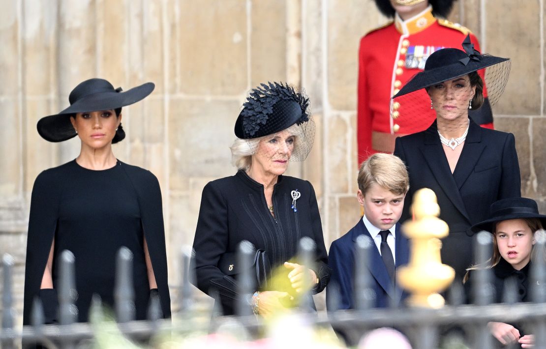 Meghan, Duchess of Sussex, Camilla, Queen Consort, Prince George of Wales, Catherine, Princess of Wales, and Princess Charlotte of Wales stand together during the Queen's funeral proceedings. 