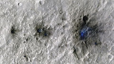 A meteoroid impact formed these craters on Mars in September 2021. This image, taken by the Mars Reconnaissance Orbiter, enhances displaced dust and soil in blue to make details more visible.