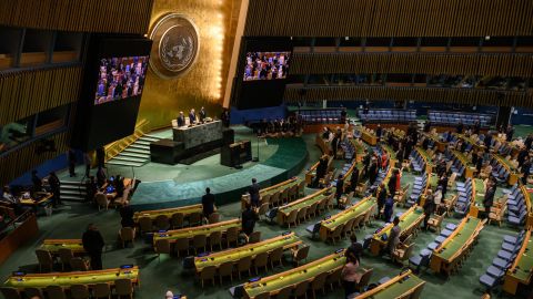 Attendees of a United Nations General Assembly meeting stand in silence during a tribute to Britain's Queen Elizabeth II, at the United Nations headquarters in New York on September 15, 2022. 