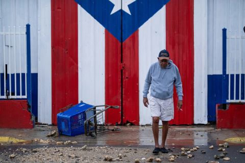 ペニュエラスのハリケーン・フィオナの余波で、ドアに描かれたプエルトリコの旗の前を通り過ぎる男性。