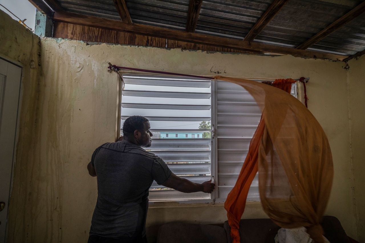 Nelson Cirino secures the windows of his home as the winds of Hurricane Fiona blow in Loíza.