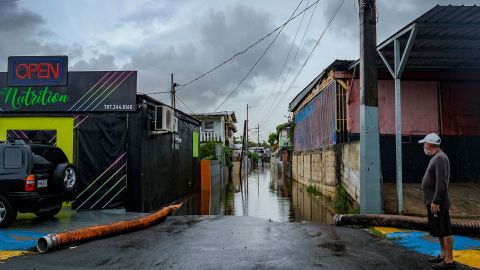 ハリケーン フィオナが通過した後、プエルトリコのカタノにあるフアナ マトス地区の浸水した通りを見る男性。 