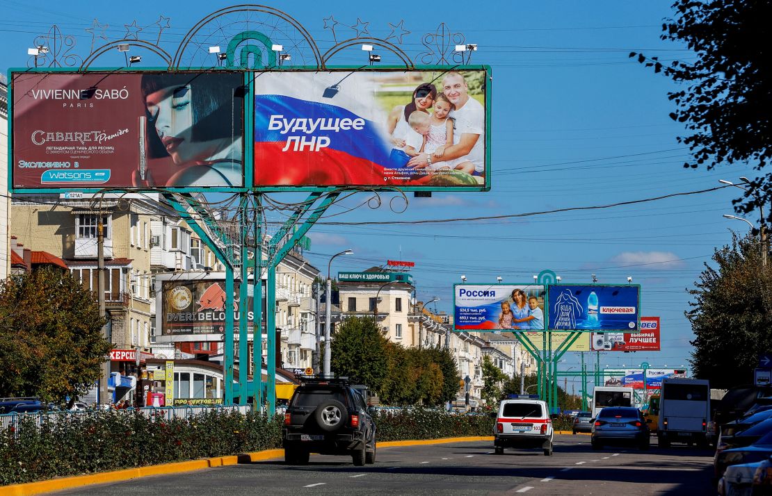 Vehicles drive past advertising boards, including panels displaying pro-Russian slogans, in Luhansk, Ukraine, on September 20.
