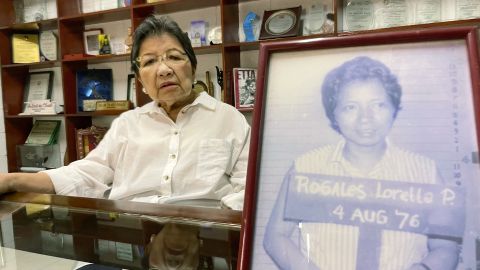 Die Menschenrechtsaktivistin Loretta Ann Rosales sitzt hinter einem grobkörnigen Militärfoto von ihr, das nach ihrer Verhaftung im Jahr 1976 aufgenommen wurde.