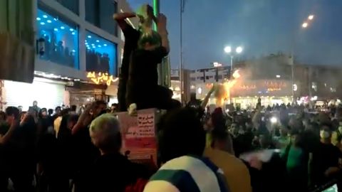 A woman in Tehran, Iran, cutting off her hair before a cheering crowd of protesters on September 20.