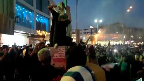 A woman in Tehran, Iran, cutting off her hair before a cheering crowd of protesters on September 20. 