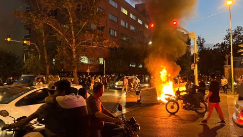 Demonstrators gather around a burning barricade during a protest for Mahsa Amini, who died after being arrested by the Islamic Republic's 