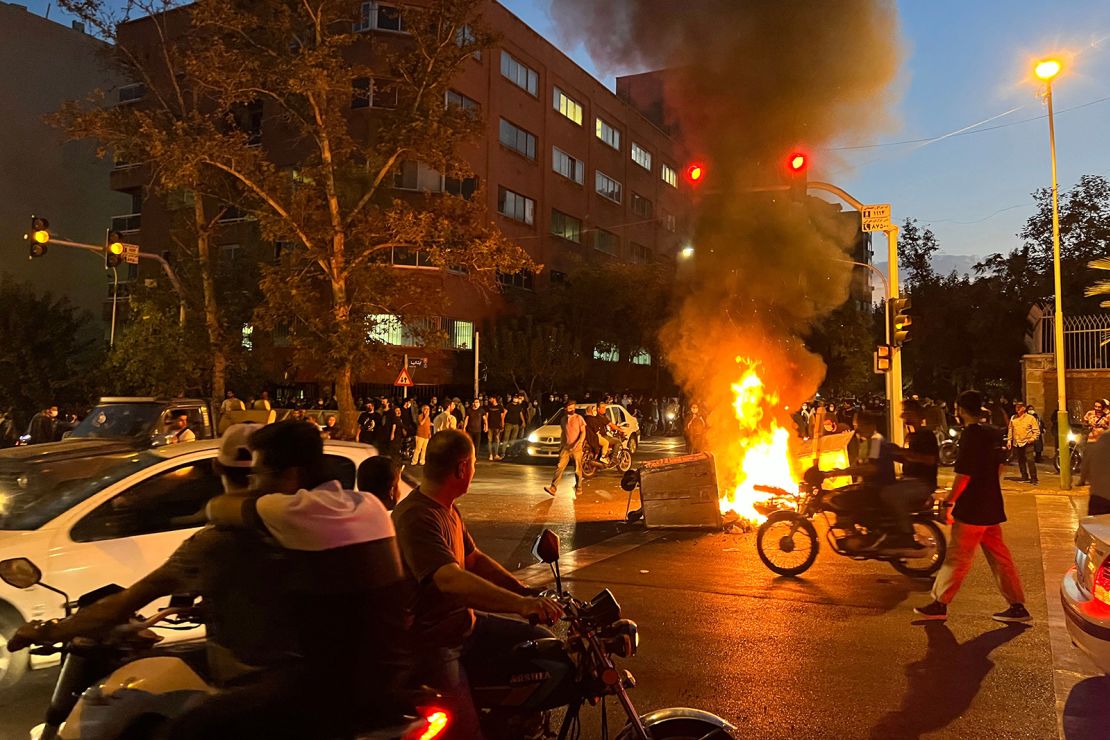Demonstrators gather around a burning barricade during a protest for Mahsa Amini, who died after being arrested by the Islamic Republic's "morality police," in Tehran on September 19, 2022. 