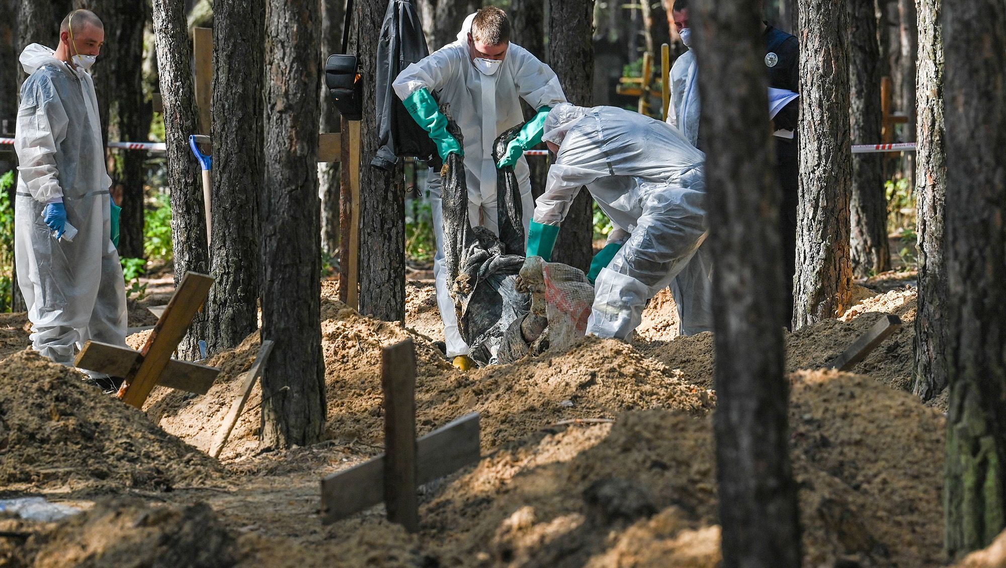 Forensic technicians operate at the site of a mass grave in a forest on the outskirts of Izyum, eastern Ukraine on September 18.