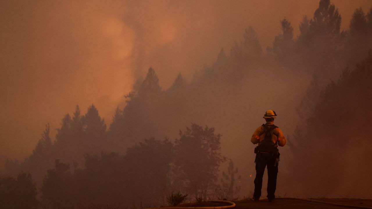 A firefighter watches the Mosquito Fire while protecting structures on September 13.