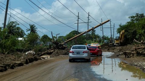 Les voitures roulent mercredi sous un poteau électrique abattu à Santa Isabel, Porto Rico.
