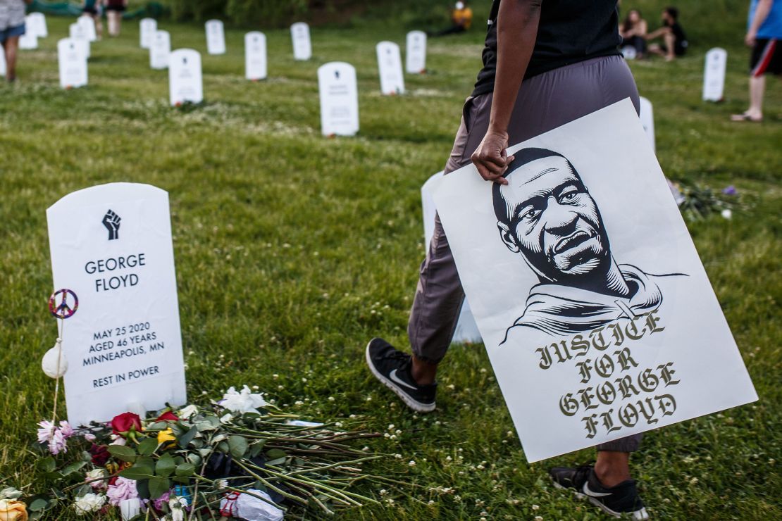 A person holds a sign displaying a portrait of George Floyd during a vigil at an art installation honoring victims of police burtaliuty in Minneapolis in June 2020. (Kerem Yucel/AFP/Getty Images)