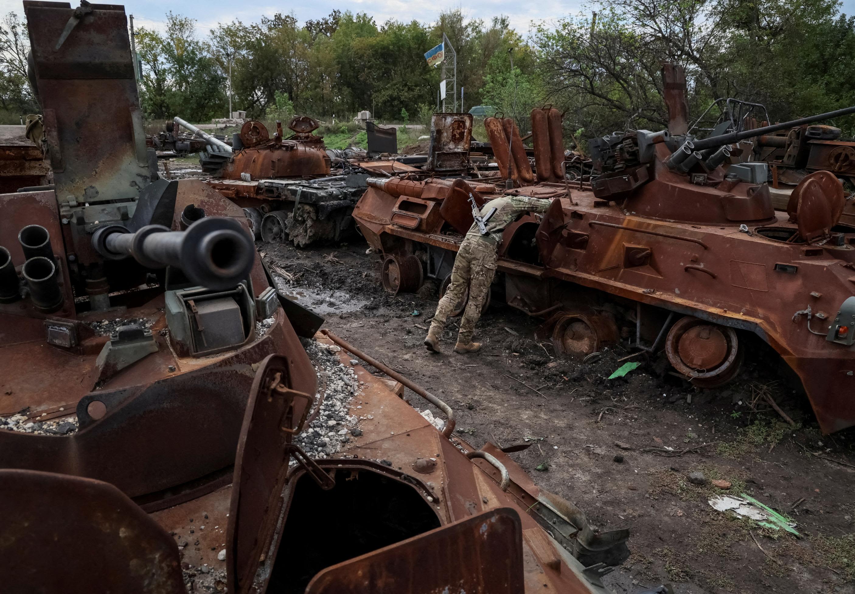 A Ukrainian serviceman checks a destroyed Russian military vehicle in the Ukrainian town of Izium on Tuesday, September 20.