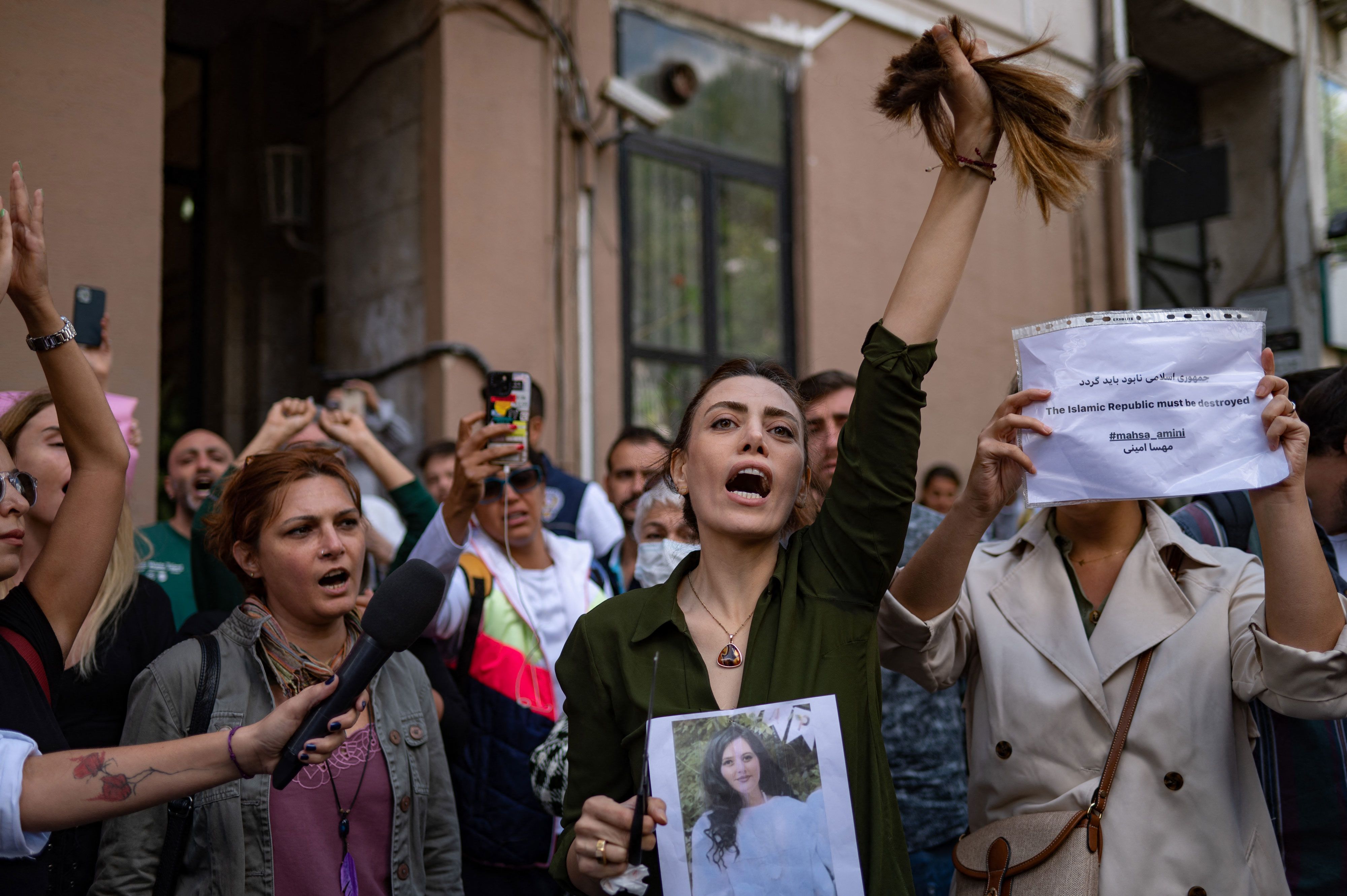 Nasibe Samsaei, an Iranian woman living in Turkey, holds up her ponytail, which she cut off with scissors while she and others protested outside the Iranian consulate in Istanbul on Wednesday, September 21.