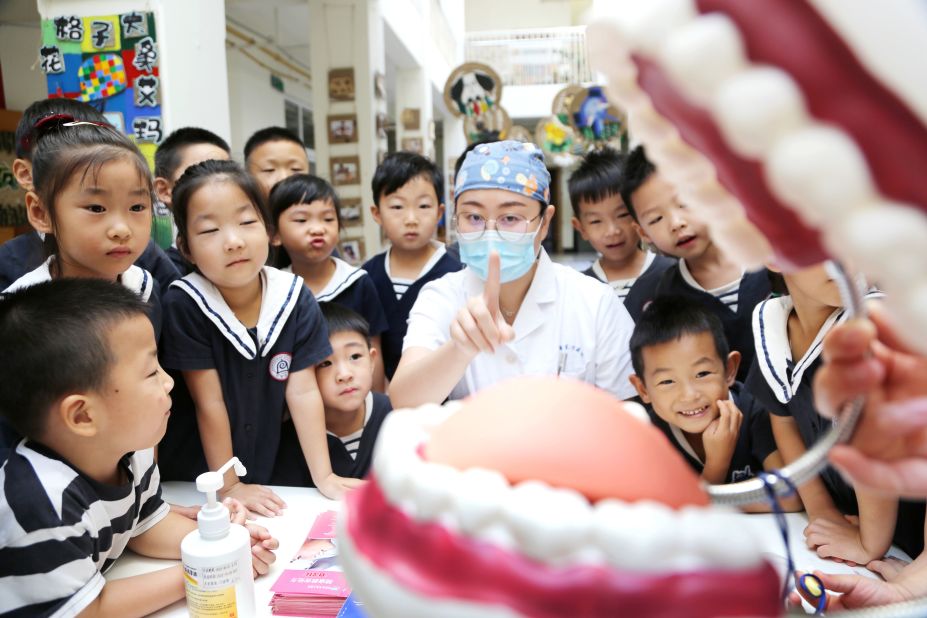 A medical worker explains dental care to children in Lianyungang, China, on Monday, September 19.