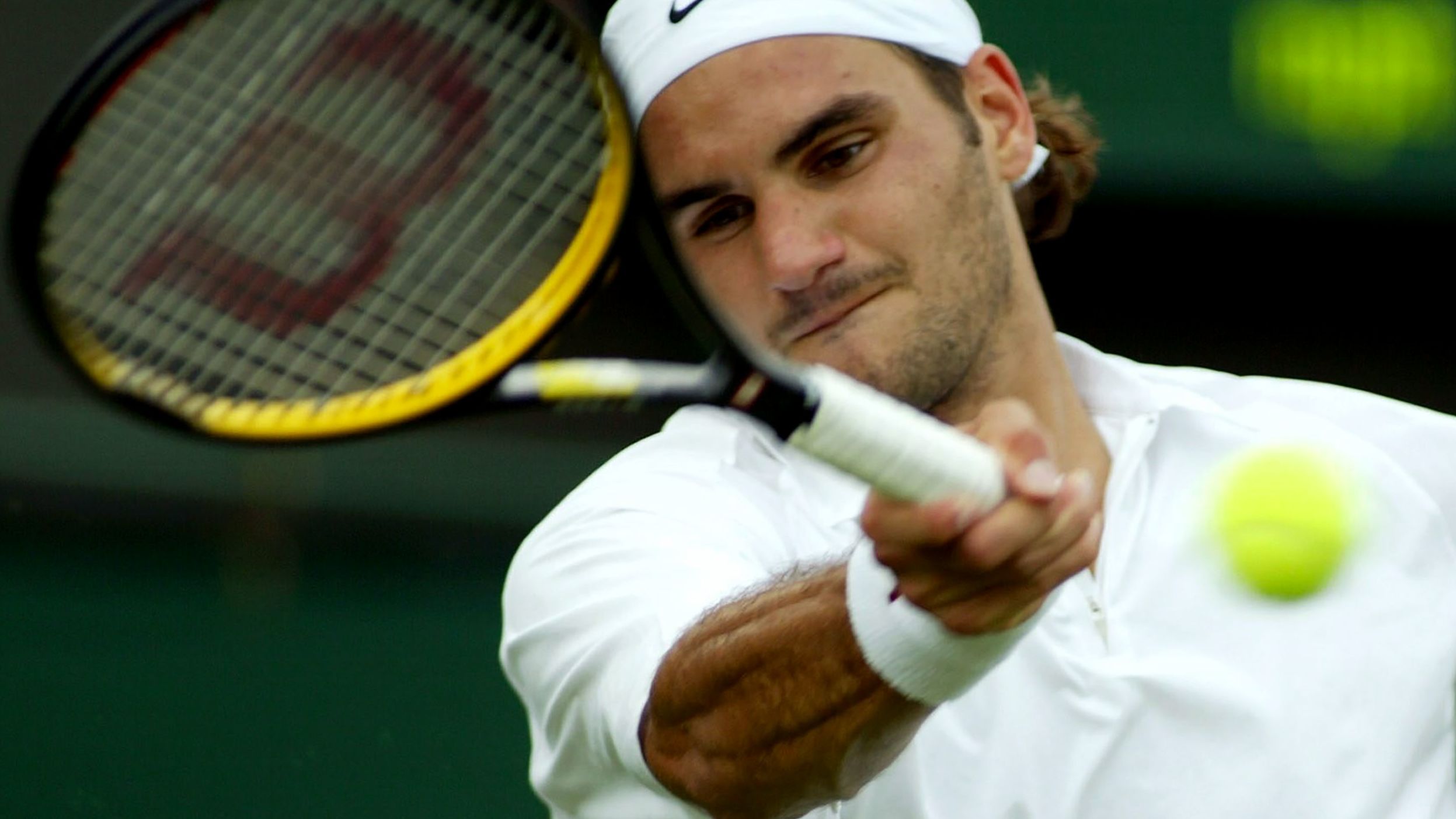 Federer hits a forehand at Wimbledon in 2003. He would go on to win the tournament, his first grand slam title.