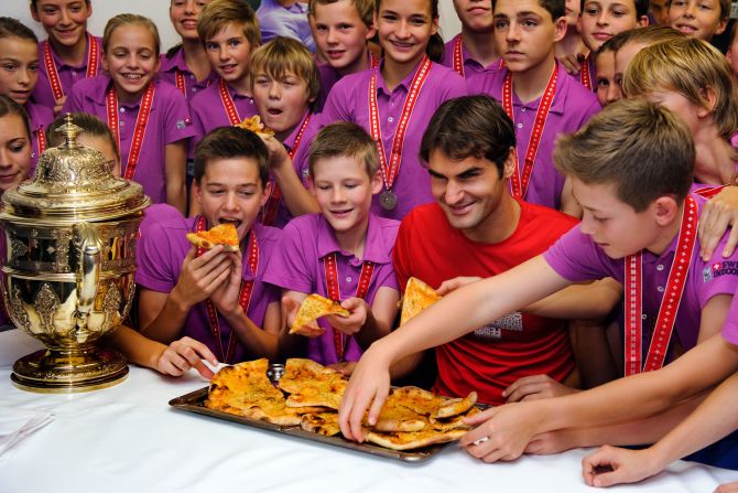 After winning a tournament in Switzerland, Federer poses with ball boys and girls as they pick up slices of pizza in 2011. Federer, who once worked as a ball boy in Basel, hosted the pizza party.