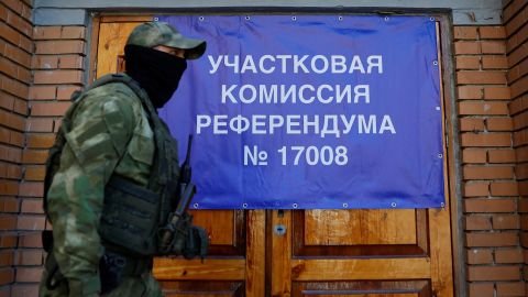 Een militair van de zelfverklaarde Volksrepubliek Donetsk passeert een spandoek bij een stembureau voorafgaand aan het geplande referendum op 22 september.