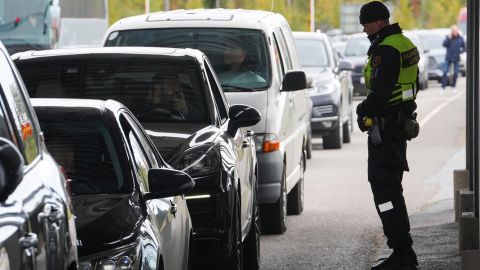 Finlandiya sınır muhafızı, 23 Eylül 2022 Cuma günü Finlandiya'nın Vaalimaa kentinde Rusya'dan Finlandiya'ya girmek için kuyruğa giren arabaların yanında duruyor.