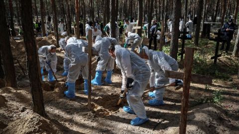 Members of the Ukrainian Emergency Service work at a mass burial site during an exhumation, in the recently liberated town of Izium of Ukraine's Kharkiv region on September 19, 2022.