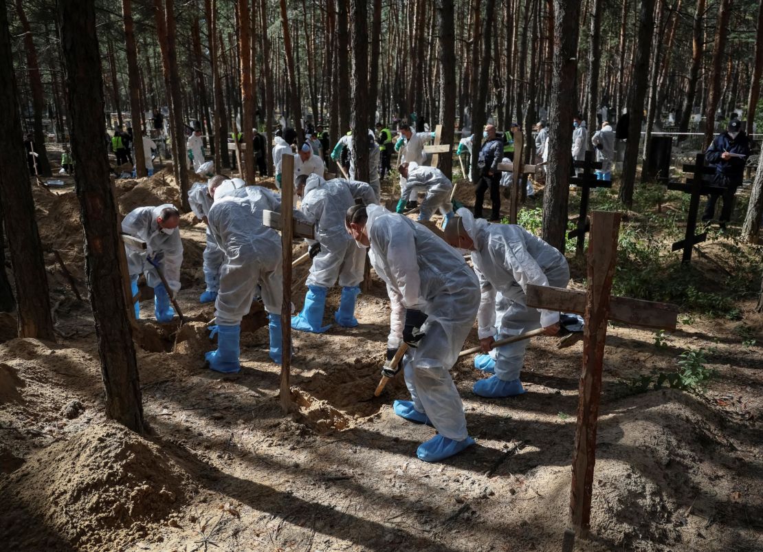 Members of the Ukrainian Emergency Service work at a mass burial site during an exhumation, in the recently liberated town of Izium of Ukraine's Kharkiv region on September 19, 2022.