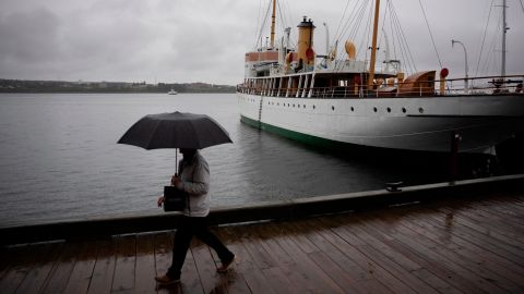 Un pedone si protegge con un ombrello mentre cammina lungo il lungomare di Halifax mentre la pioggia cade davanti al ciclone Fiona che atterra ad Halifax, venerdì 23 settembre 2022.