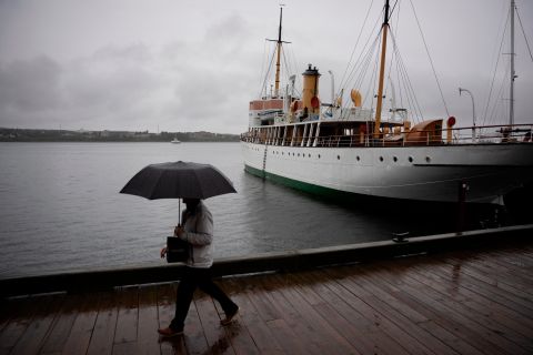 Pieszy zasłaniał się parasolem podczas spaceru wzdłuż nabrzeża Halifaxu w piątek.