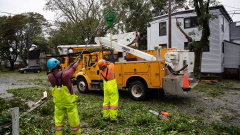 Les travailleurs soulèvent un fil coupé pour permettre aux machines d'atteindre les arbres à feuilles caduques à Halifax, en Nouvelle-Écosse, samedi.