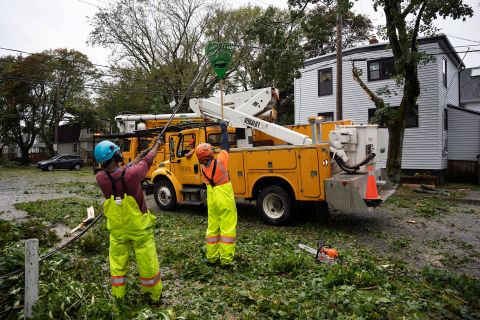 Workers lift fallen wires to allow machines to reach fallen trees in Halifax on Saturday.