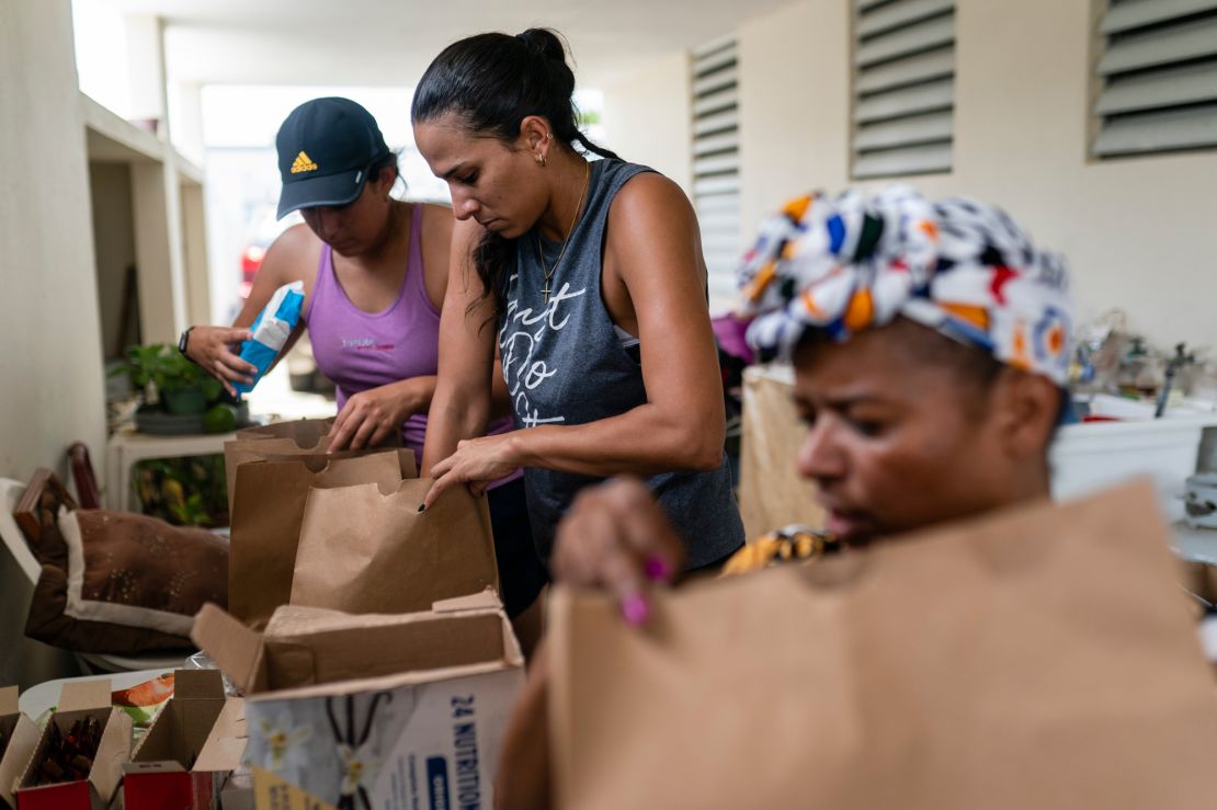 From left, Tatiana Pacheco, Maria Pacheco and Modesta Irizarry pack bags of food for Irizarry's elderly neighbors.